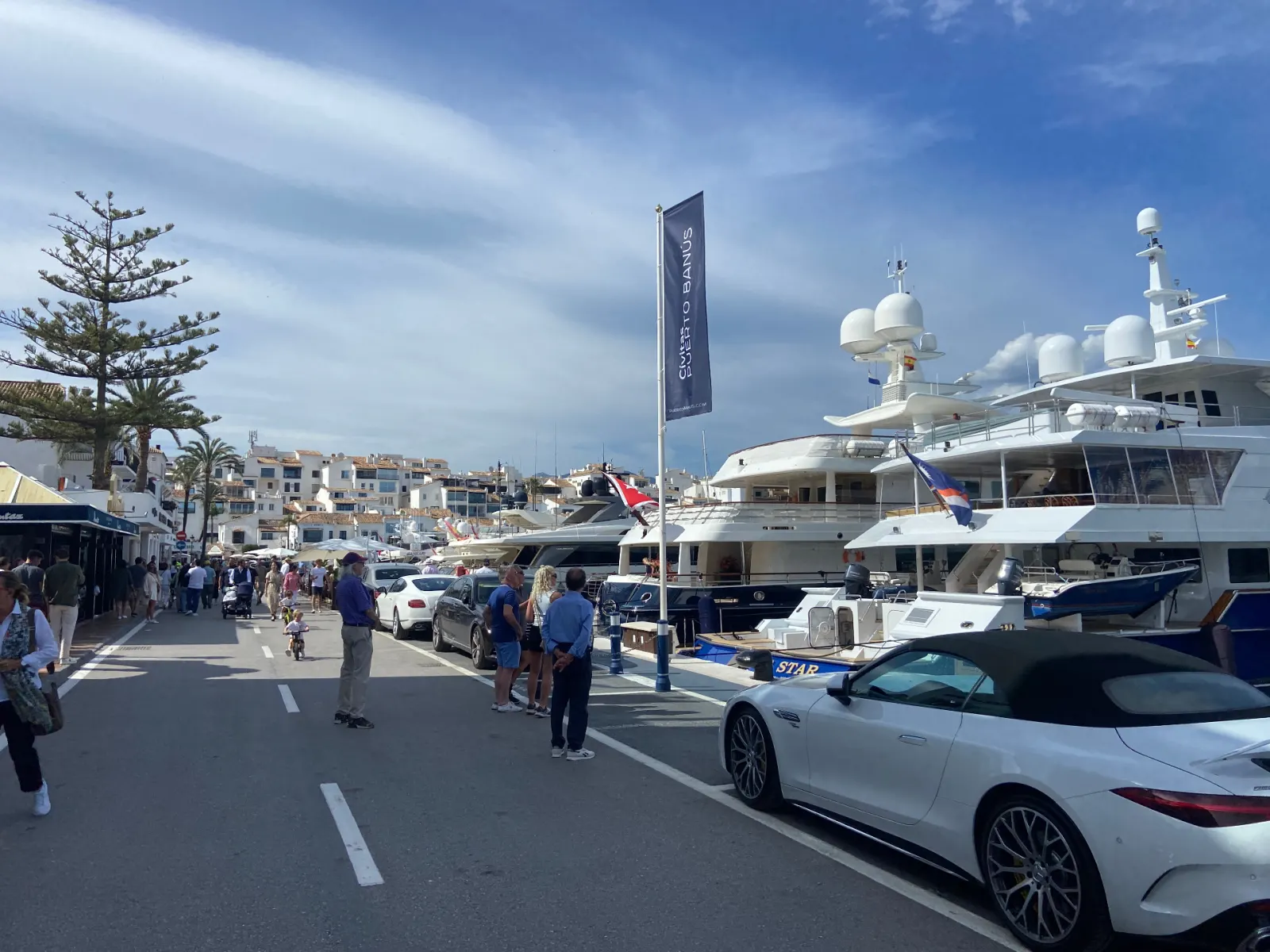 Superyachts moored along the Puerto Banús marina under the Civitas Puerto Banús flag